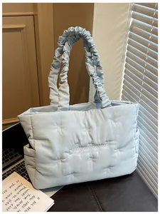 Light blue quilted nylon tote bag featuring delicate white bow embroidery and pleated strap
