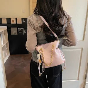 Pink quilted bucket bag with gold chain and horse charm shown in lifestyle setting