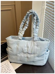 Close-up of light blue quilted tote bag with white bow embroidery and ruffled shoulder strap