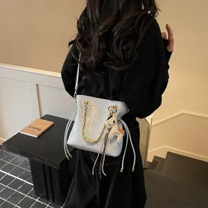Quilted light blue bucket bag with gold chain and horse charm for spring fashion wear