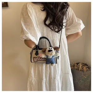 Close-up of canvas Boston bag with MISS GAIL embroidery and cute dog plush charm