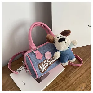 Close-up of blue denim Boston bag with pink leather trim and cute puppy plush charm