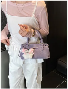 Detail of purple bucket bag with plush bunny charm and metallic fashion brand tag
