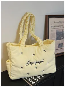 Detail of light yellow quilted nylon tote bag with black bows and ruffled handles