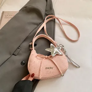 Detail van roze handtas met sterrenpatroon, zilveren sterhanger en verstelbare riem