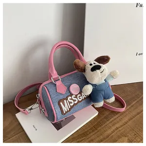 Detail of blue denim Boston bag with pink leather trim and cute puppy plush charm