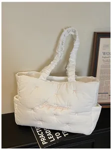 Detail of white quilted nylon tote bag with pink bow embroidery and pleated cloud handle