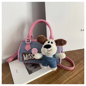 Detailed close-up of a mini denim Boston bag featuring a plush puppy charm on a wooden desk