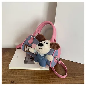 Detail of blue denim Boston bag with pink leather handles and cute plush dog charm