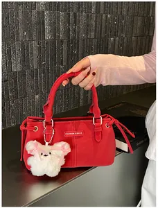Detail of red leather tote bag with a fashion logo and a cute white bear keychain accessory