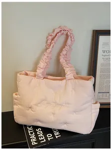 Detail of light pink quilted nylon tote featuring ruched handle and bow embroidery
