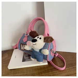 Detail of blue denim Boston bag with pink leather trim and a cute plush puppy doll