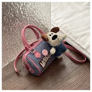 Detail of blue denim Boston bag with pink leather straps and a cute plush dog pendant