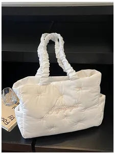 Macro detail of white quilted nylon tote with pink bow embroidery and ruffled handle