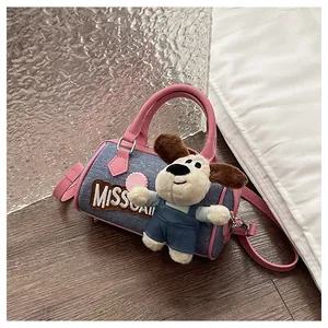 Detail of blue denim and pink leather Boston bag with a cute plush dog pendant charm