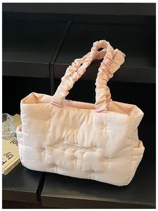 Detail of pink quilted nylon tote featuring bow embroidery and scrunchie handles