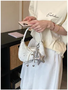 Detail van witte Y2K-stijl crossbodytas met sterpatroon en zilveren sterhanger