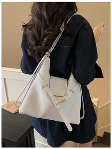 Detailaanzicht van een lichtgrijze waxlederen tote bag gedragen op de schouder van een model