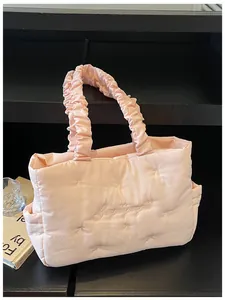 Detail of light pink quilted tote bag with bow stitching and ruched handle design