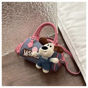 Close-up of blue denim Boston bag with pink leather trim and a cute plush dog charm