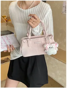 Detail of pink faux leather bucket bag with metal logo and cute puppy pendant accessory