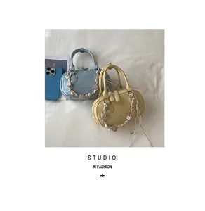 Close-up of minimalist leather handbags in blue and yellow with beaded straps and wood beads