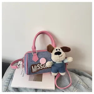 Detail of denim Boston bag with pink leather trim and cute puppy plush pendant