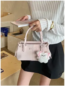 Detail of light pink bucket bag featuring a white teddy bear charm and silver hardware