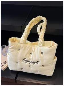 Detail of light yellow nylon tote bag with black bow embroidery and ruffled handles