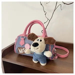 Close-up of denim Boston bag with pink leather handles and cute plush puppy charm