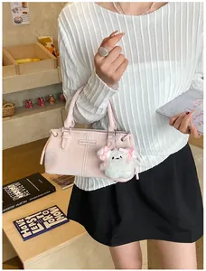 Detail of light pink shoulder bag with metal logo and cute puppy pendant on model
