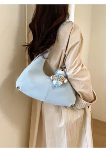 Détail du sac hobo bleu clair avec texture mate et breloque ours en peluche sur l'anse