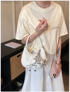 Detail van een witte halve maan crossbody tas met zilveren sterrenprint en hanger