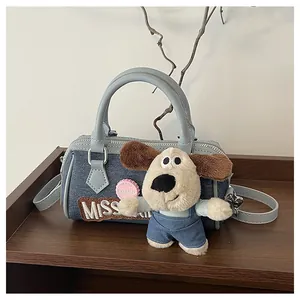 Detail of light blue denim Boston bag with cartoon plush pendant and MISS embroidery