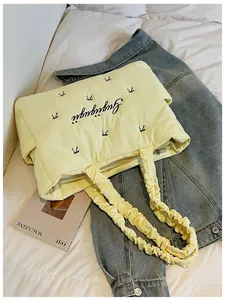 Close-up of quilted nylon tote bag featuring bow embroidery and ruffled handle detail
