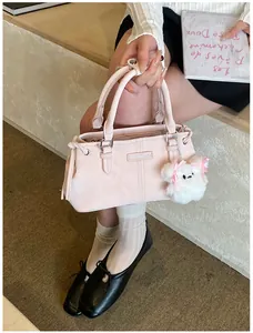 Detail of light pink leather bucket bag with cute white plush charm and metal logo