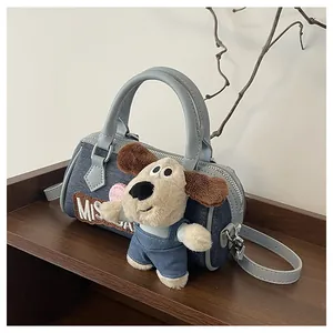 Detail of denim Boston bag with puppy plush charm, embroidery and leather trim