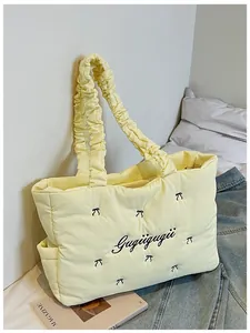 Detail of light yellow quilted tote bag with bow embroidery and ruffled handle design