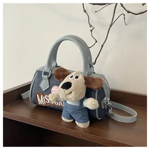 Detail of a mini denim Boston bag with a leather handle and a cute plush dog pendant