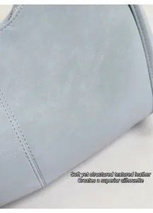 Gros plan sur cuir bleu clair à motif lychee avec coutures fines et fermeture éclair argent