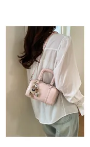 Light pink Boston bag featuring decorative pearls and heart charms shown on a model
