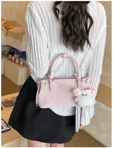 Detail of pink leather bucket bag with plush bear charm and detachable strap