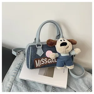Detailed close-up of blue denim Boston bag with cute plush puppy charm and letter embroidery