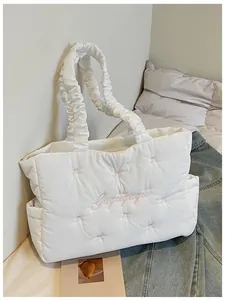 Detail of white quilted nylon tote with pink bow embroidery and ruffled handle design