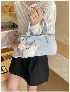 Detail of light blue bucket bag with fluffy rabbit charm and fashion logo plaque