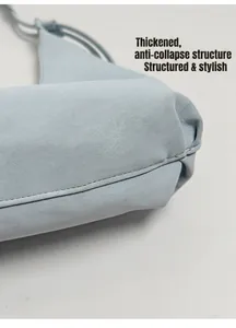 Vue détaillée de la base renforcée d'un sac à main bleu clair en cuir plissé