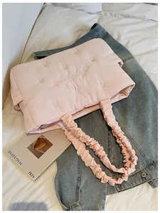 Close-up of pink quilted nylon tote bag with floral embroidery and ruched handles