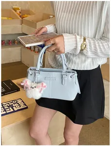 Detail of light blue leather bucket bag with cute white plush dog charm and soft stitching