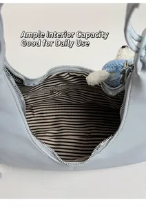 Détail du sac bandoulière bleu clair avec doublure rayée et bijou de sac chien