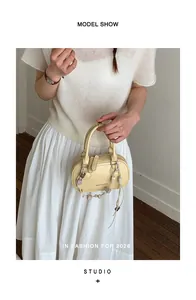 Detail of light yellow leather handbag featuring brand lettering and heart charm ornament